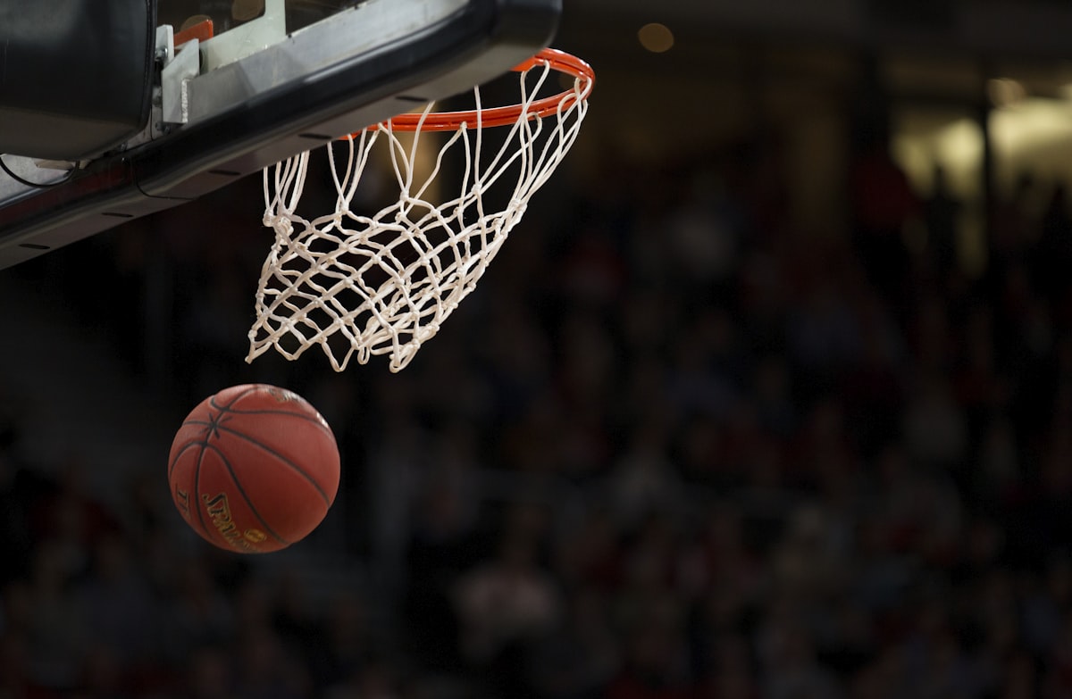 A basketball dropping through the net in a packed arena