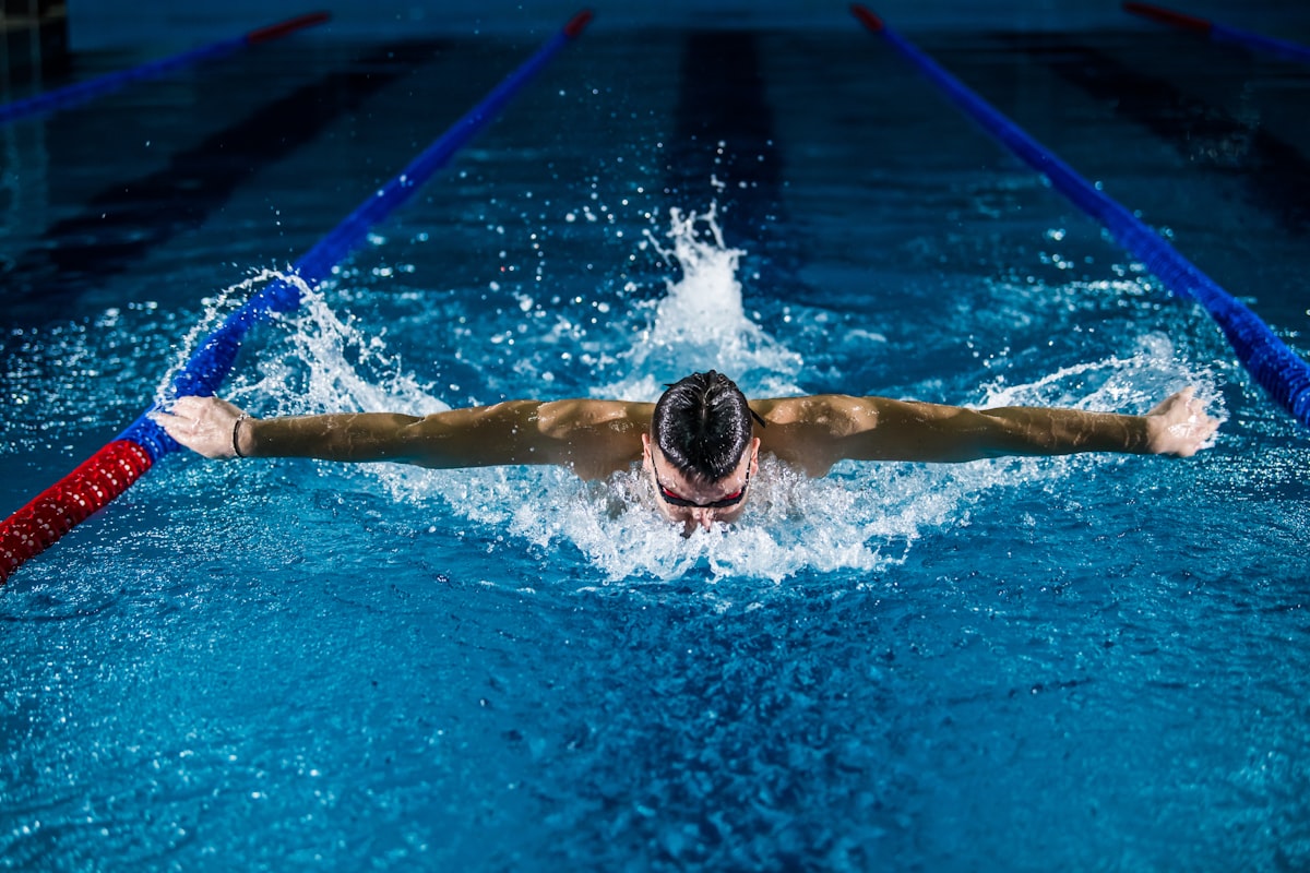 A butterfly swimmer mid-stroke, water flying
