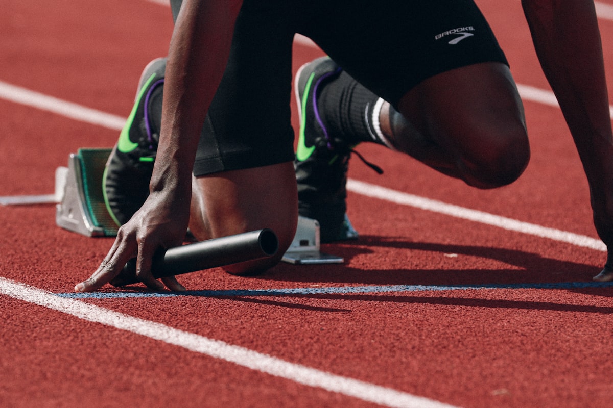 A sprinter set in the blocks, baton in hand